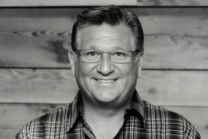 Smiling counsellor, black-and-white headshot on wood backdrop