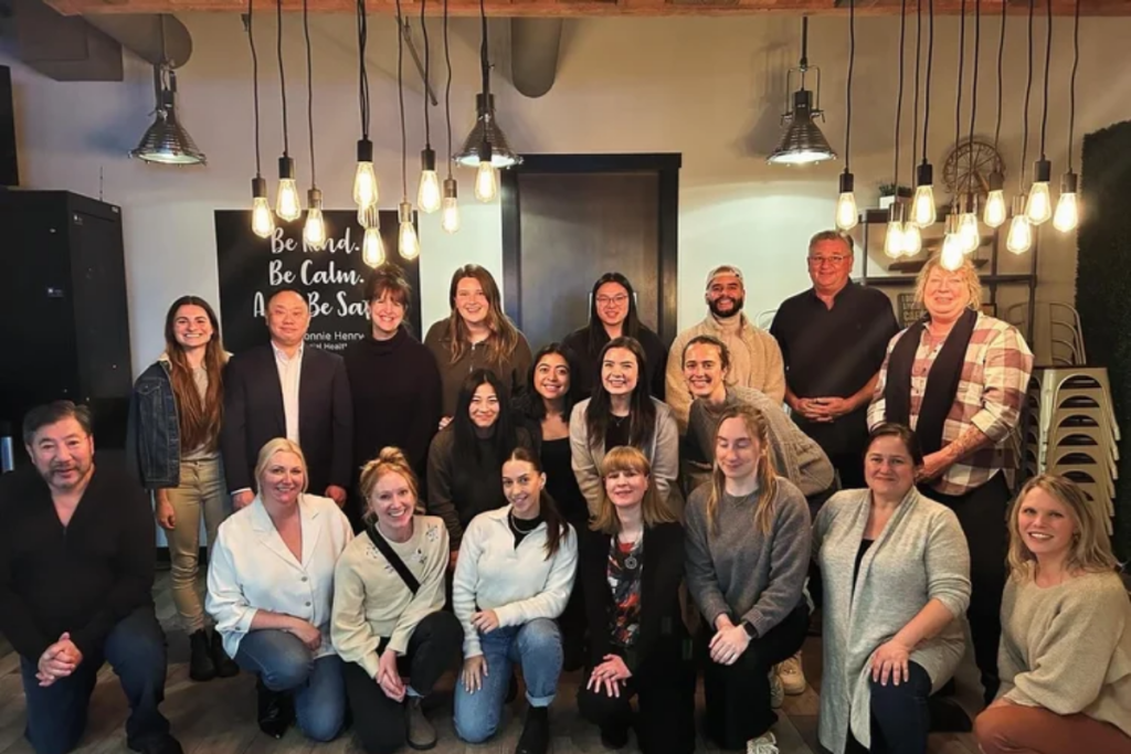 Group photo of diverse adults in an indoor meeting space under hanging lights